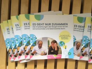 mehrere Exemplare der Mini-Broschüre zum Klima-Aktionsplan der Bürger:innen