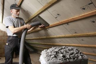 eine Person dämmt einen Dachstuhl