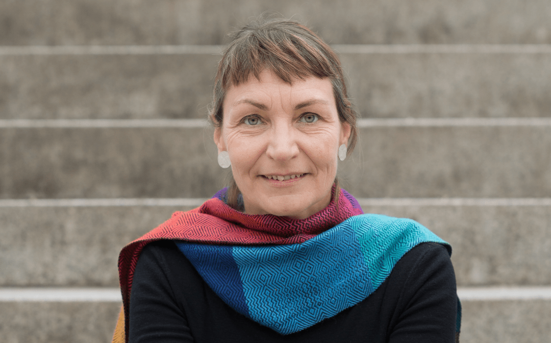 Transition Trainerin Gesa Maschkowski sitzt auf einer Treppe und lächelt